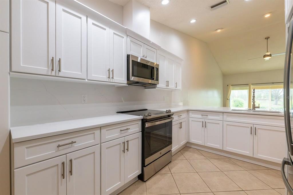 A kitchen with white cabinets, stainless steel appliances, and light-colored countertops and tile flooring — 12235 SW KINGSWAY CIRCLE UNIT C6, ARCADIA, FL
