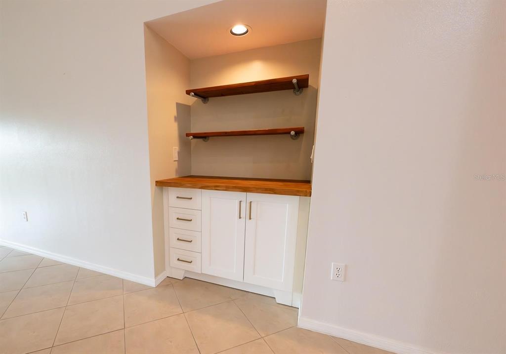 A built-in wet bar features white cabinets, a wood countertop, and two floating shelves — 12235 SW KINGSWAY CIRCLE UNIT C6, ARCADIA, FL