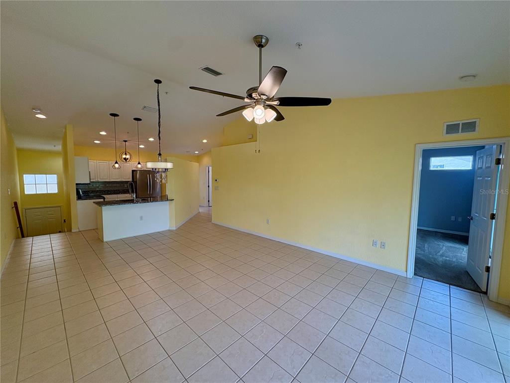 An open-concept living area features yellow walls, tile flooring, a ceiling fan, and a kitchen — 6421 BAY CEDAR LANE, BRADENTON, FL