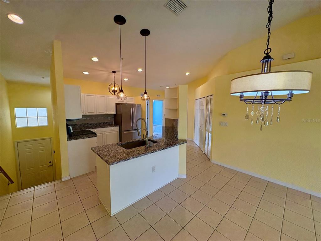 A kitchen with granite countertops and white cabinets overlooks a dining area with tile floors — 6421 BAY CEDAR LANE, BRADENTON, FL