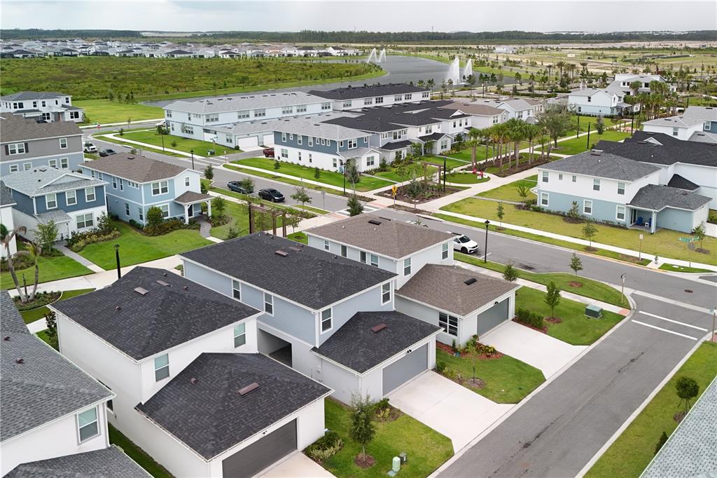 An aerial view shows a suburban neighborhood with multi-story houses, paved streets, and a pond — 10922 FELICITY ALLEY, ORLANDO, FL