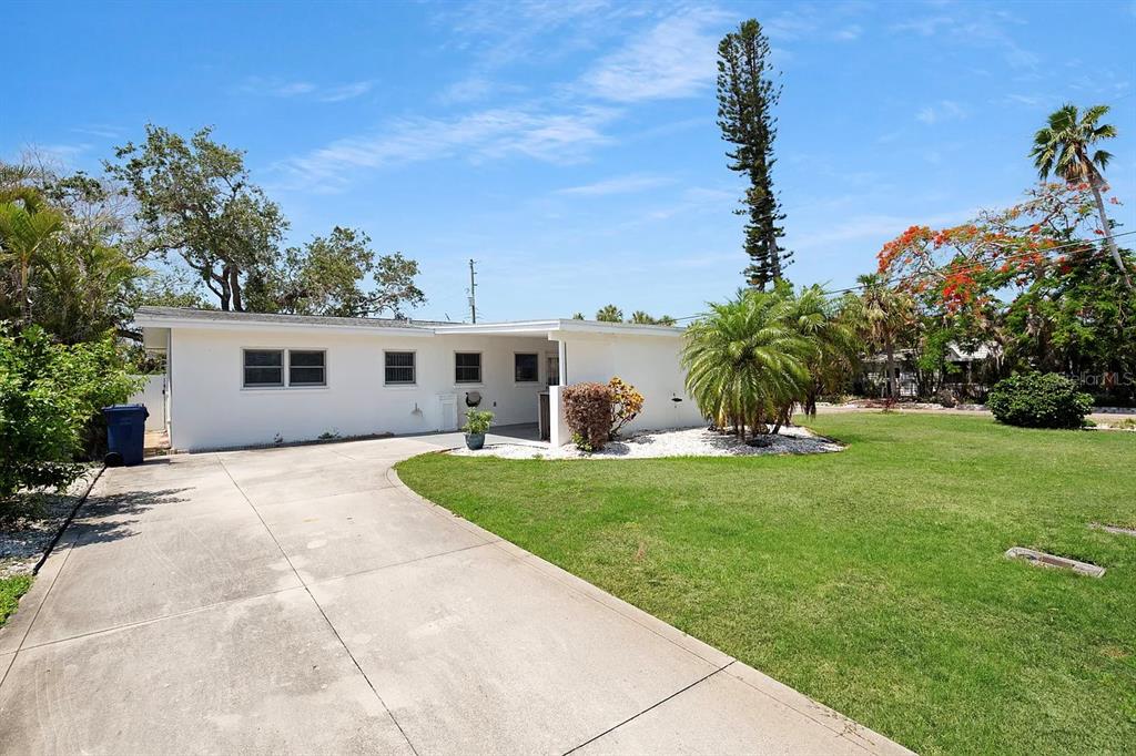 A white single-story house features a concrete driveway, a small covered patio, and a lawn — 301 41ST AVENUE, ST PETE BEACH, FL