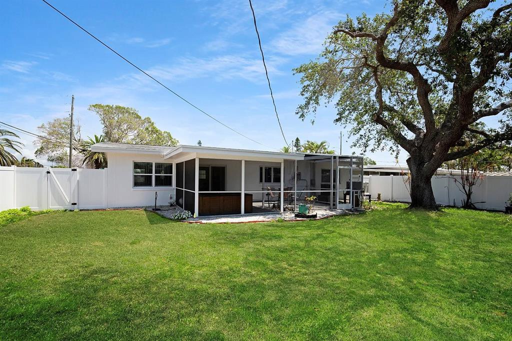 A white house with a screened-in patio and a large tree in the backyard — 301 41ST AVENUE, ST PETE BEACH, FL