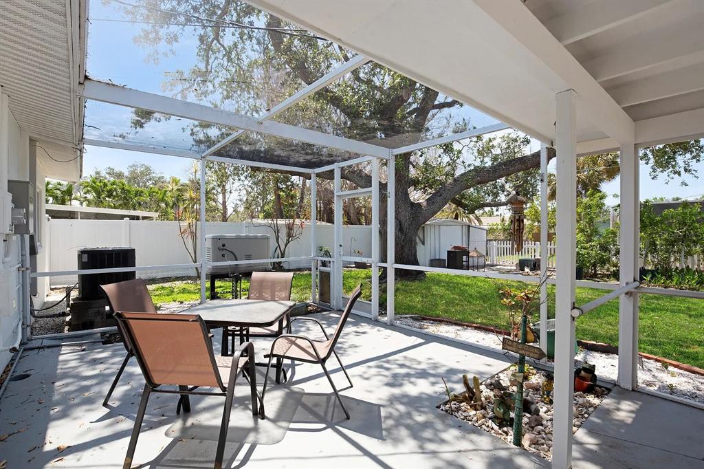 A screened-in patio with a dining set overlooks a backyard with a large tree — 301 41ST AVENUE, ST PETE BEACH, FL