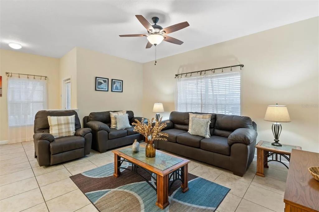 A living room features dark leather furniture, a glass-topped coffee table, and tile flooring — 3071 BEACH PALM AVENUE, KISSIMMEE, FL