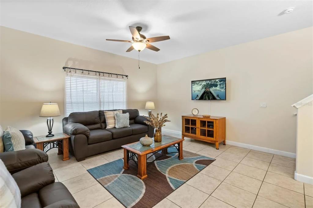 A living room features tile flooring, a dark sofa, a coffee table, and a ceiling fan — 3071 BEACH PALM AVENUE, KISSIMMEE, FL