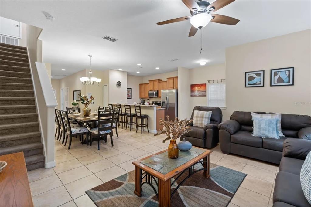An open-concept living and dining area features tile flooring, a staircase, and a kitchen — 3071 BEACH PALM AVENUE, KISSIMMEE, FL