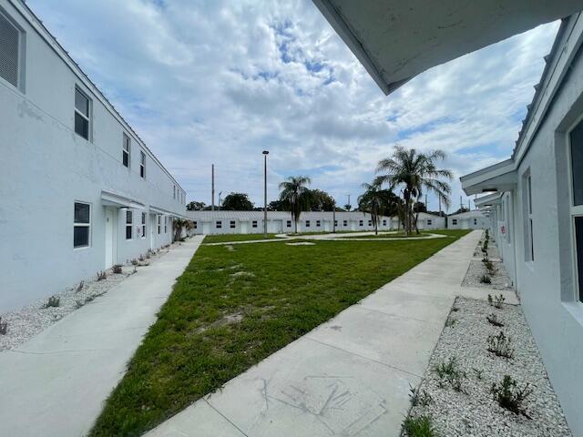 Exterior view of a white apartment complex with a central grassy courtyard and walkways — 4393 Windsor Avenue # 2, West Palm Beach FL 33407, WEST PALM BEACH, FL
