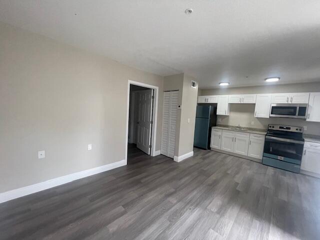 A kitchen with white cabinets and stainless steel appliances opens to a living area — 4393 Windsor Avenue # 2, West Palm Beach FL 33407, WEST PALM BEACH, FL