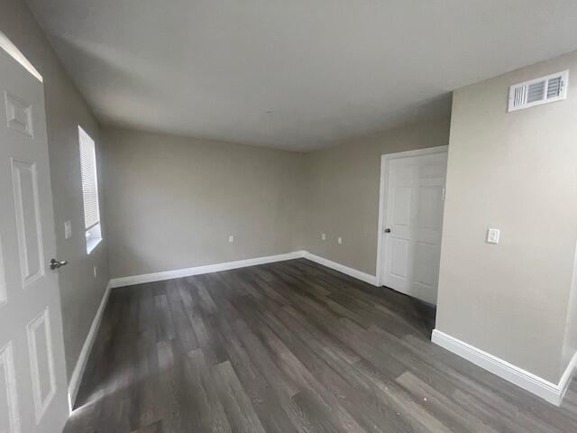 An empty room with gray walls, wood-look flooring, a window, and two white doors — 4393 Windsor Avenue # 2, West Palm Beach FL 33407, WEST PALM BEACH, FL