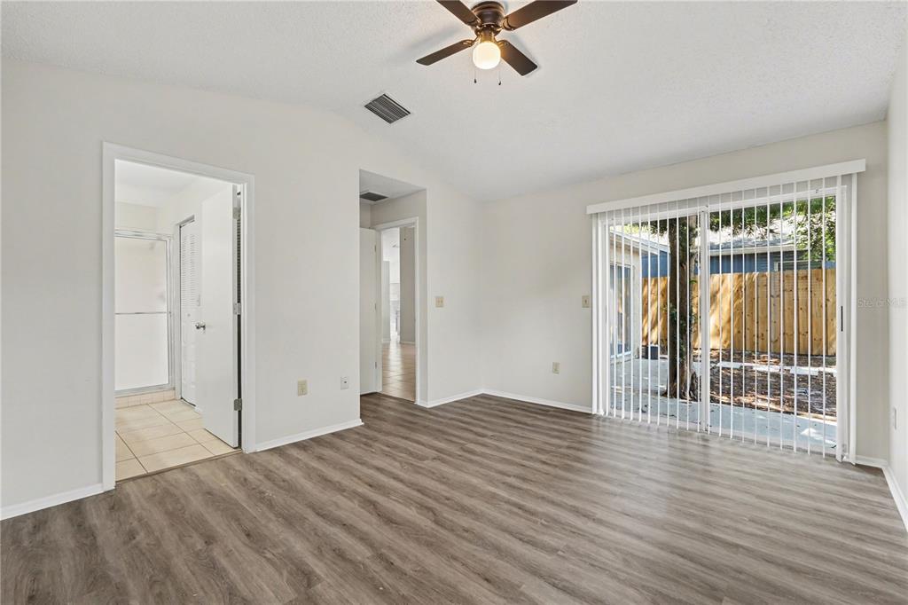 A bedroom with wood-look flooring, a ceiling fan, and sliding glass doors to a patio — 13618 LARAWAY DRIVE, RIVERVIEW, FL