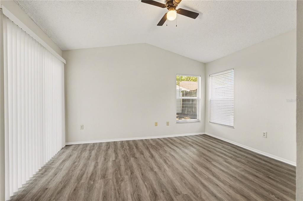 An empty room with light gray walls, wood-look flooring, a ceiling fan, and two windows — 13618 LARAWAY DRIVE, RIVERVIEW, FL