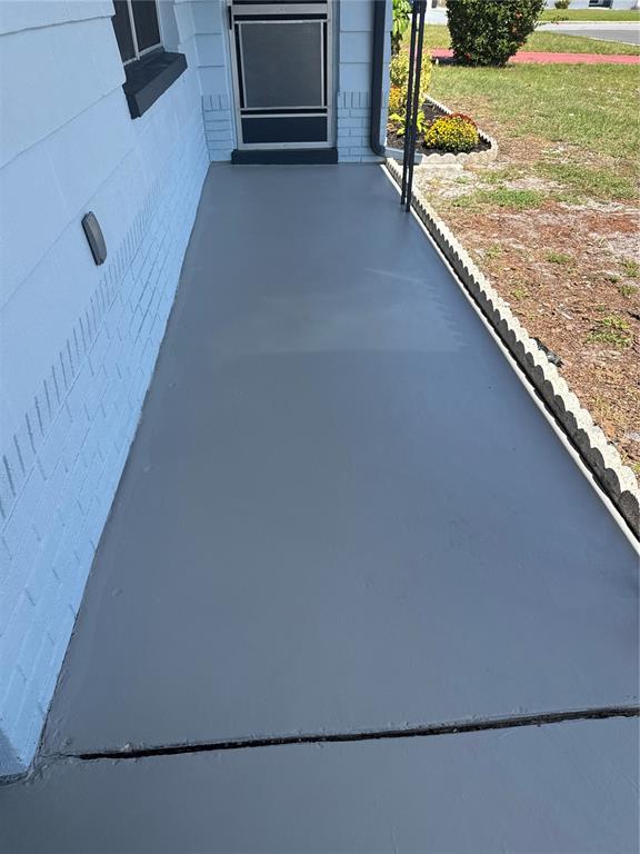 A freshly painted gray concrete porch leads to a front door with a screen — 3447 COLUMBUS DRIVE, HOLIDAY, FL