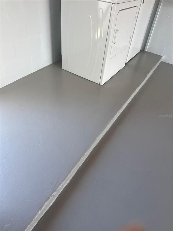 A white dryer sits on a gray painted floor in a room with block walls — 3447 COLUMBUS DRIVE, HOLIDAY, FL