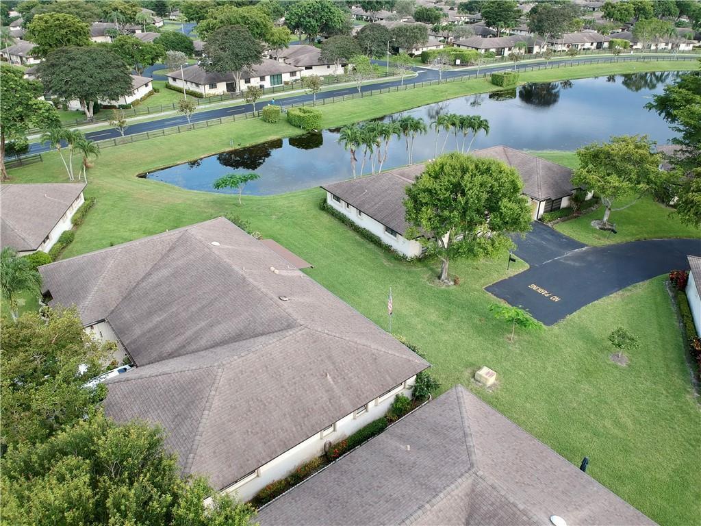 An aerial view shows residential buildings with brown roofs situated near a small lake — 10151 Eaglewood Terrace # A, Boynton Beach FL 33436, BOYNTON BEACH, FL