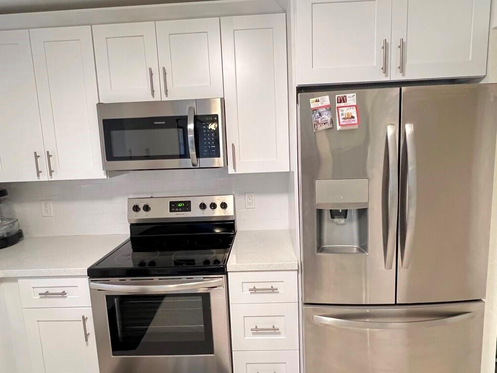 A kitchen features white shaker cabinets, stainless steel appliances, and light-colored countertops — 10151 Eaglewood Terrace # A, Boynton Beach FL 33436, BOYNTON BEACH, FL