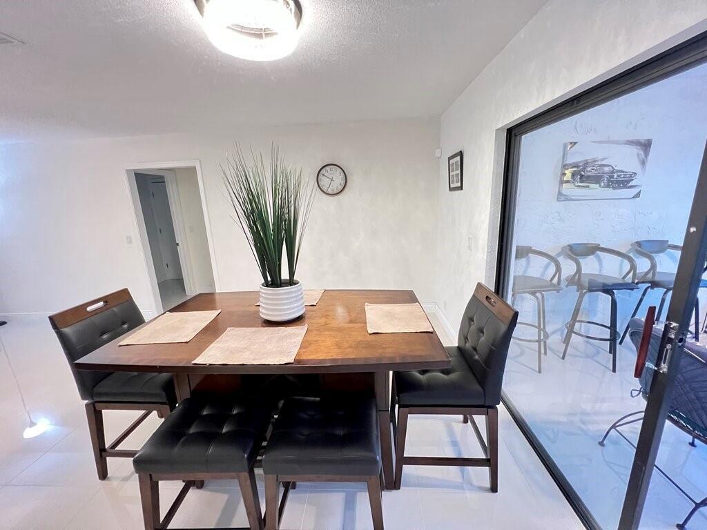 A dining area features a wooden table with black chairs and a tall plant centerpiece — 10151 Eaglewood Terrace # A, Boynton Beach FL 33436, BOYNTON BEACH, FL