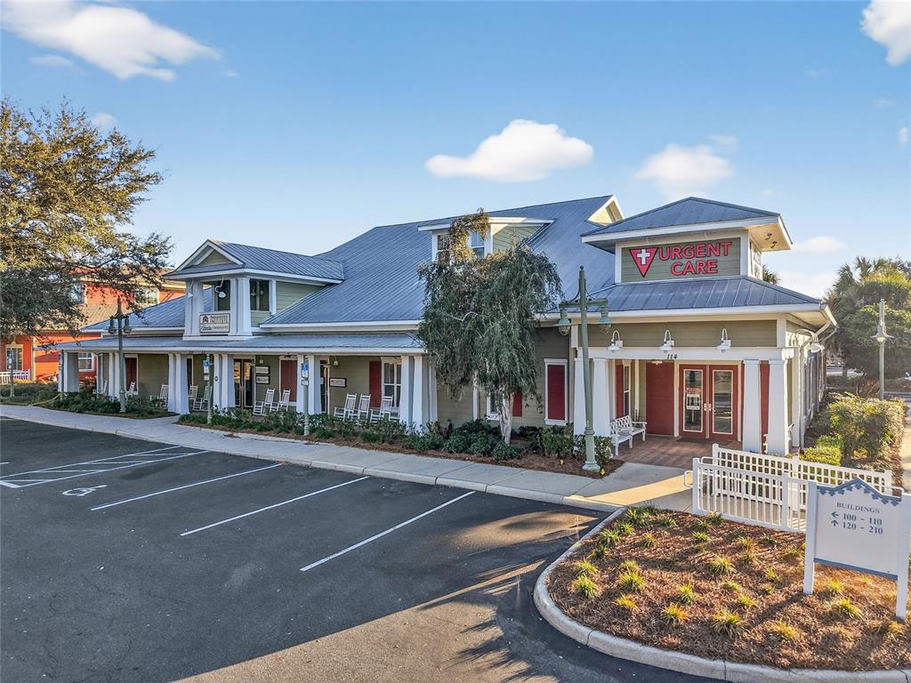 An exterior view of a commercial building with a metal roof and urgent care signage — 910 OLD CAMP ROAD UNIT 110, THE VILLAGES, FL