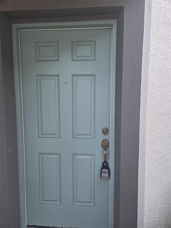A light blue, six-panel front door with a lockbox attached to the handle — 2802 NARCOOSSEE COMMONS WAY, ST CLOUD, FL