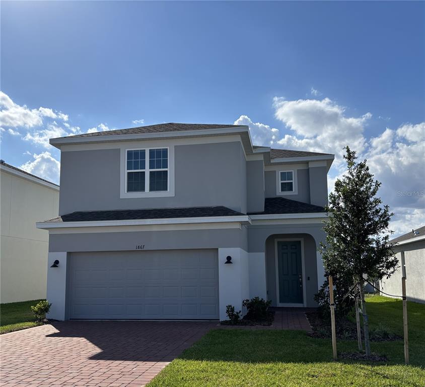 A two-story house with a gray stucco exterior, a two-car garage, and a paved driveway — 1867 CHURCH LAKE STREET, GROVELAND, FL