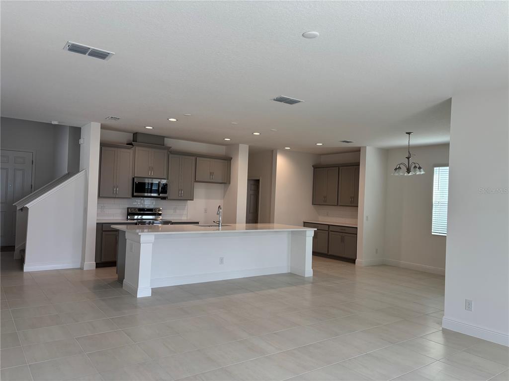 A modern kitchen features gray cabinets, a white island, and tile flooring in an open space — 1867 CHURCH LAKE STREET, GROVELAND, FL