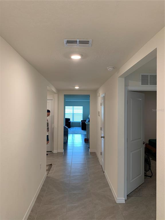 A hallway with tile flooring leads to a living area with a window — 10305 SE 161ST STREET, SUMMERFIELD, FL