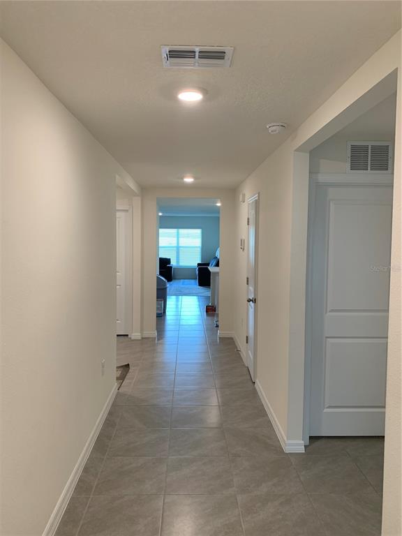 A tiled hallway leads from the foreground toward a living area with a window — 10305 SE 161ST STREET, SUMMERFIELD, FL