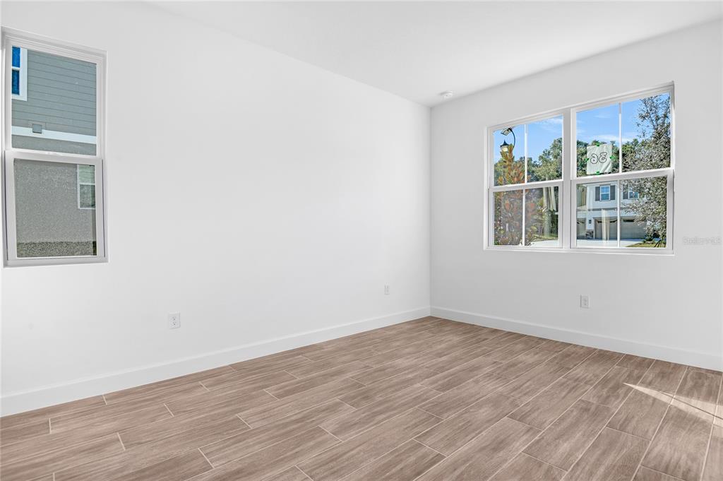 An empty room with white walls, wood-look tile flooring, and two windows — 748 WEKIVA RIDGE DRIVE, MOUNT DORA, FL