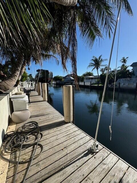 A wooden dock extends over a canal with palm trees and boats in the background — 1361 NE 27 Way, Pompano Beach FL 33062, POMPANO BEACH, FL