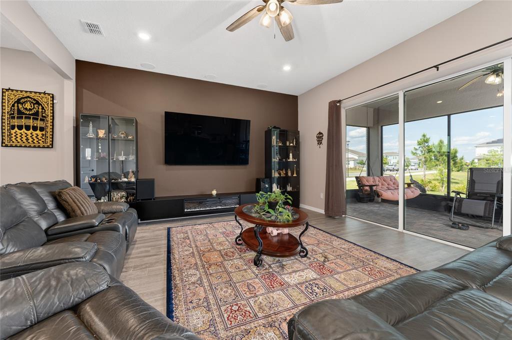 A living room features a dark brown accent wall, leather sofas, and sliding glass doors — 13615 RITTA ISLAND DRIVE, ORLANDO, FL