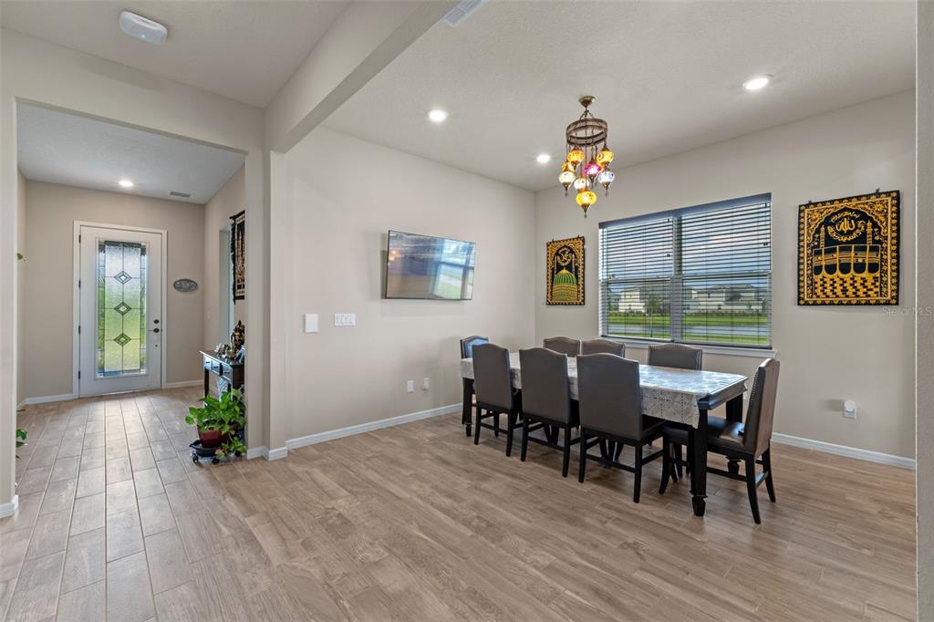 A dining room with a long table, six chairs, a chandelier, and wall-mounted Islamic artwork — 13615 RITTA ISLAND DRIVE, ORLANDO, FL