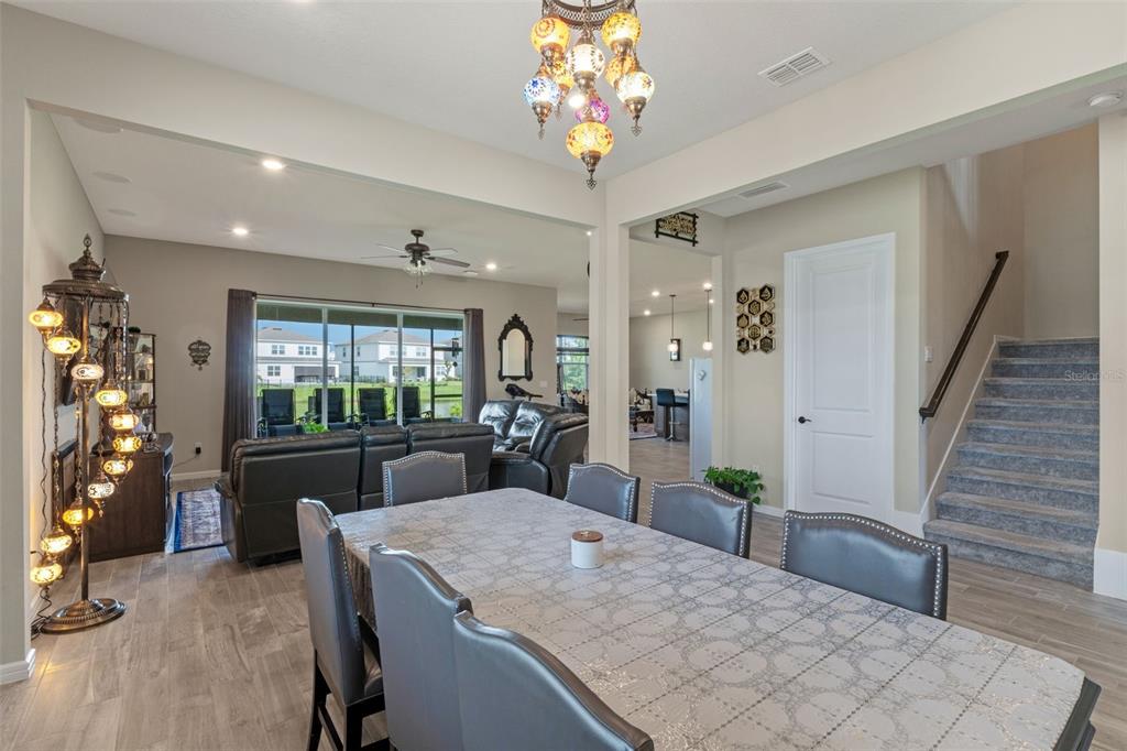A dining room with a patterned table and mosaic chandelier opens into a living area — 13615 RITTA ISLAND DRIVE, ORLANDO, FL