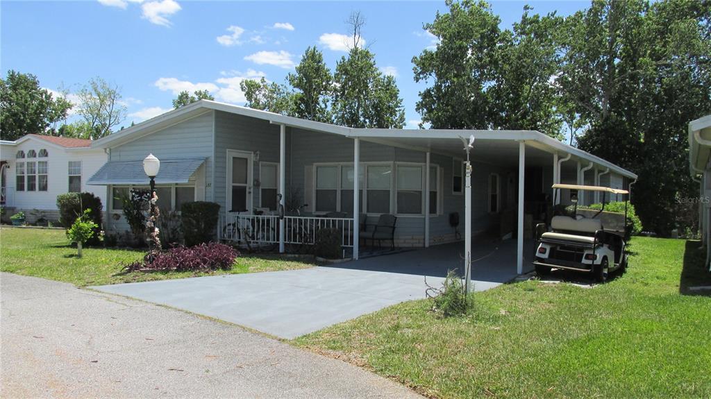 A light blue mobile home features a covered carport, a front porch, and a golf cart — 157 VICTORIA DRIVE, HAINES CITY, FL