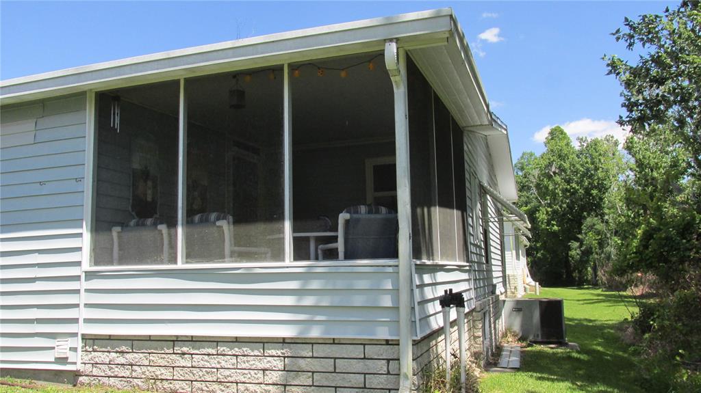 A screened-in porch with light blue siding and a brick base sits on the side of a house — 157 VICTORIA DRIVE, HAINES CITY, FL