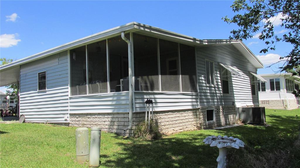 A light blue mobile home features a screened-in porch and a concrete block foundation — 157 VICTORIA DRIVE, HAINES CITY, FL