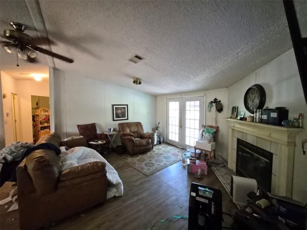 A living room features wood-look flooring, a fireplace, a ceiling fan, and glass patio doors — 21508 NW 190TH AVENUE, HIGH SPRINGS, FL