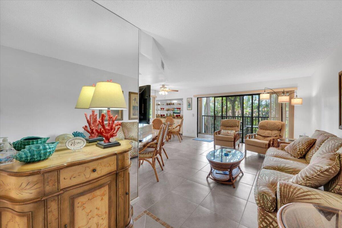 A living room features tile flooring, a mirrored wall, wicker furniture, and a sliding glass door — 1605 S Us Highway 1 # E201, Jupiter FL 33477, JUPITER, FL