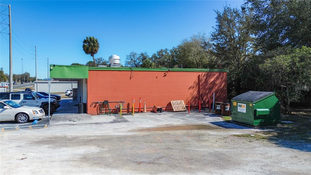 The exterior of a commercial building with an orange wall, green trim, and a dumpster — 3030 W GULF TO LAKE HIGHWAY, LECANTO, FL