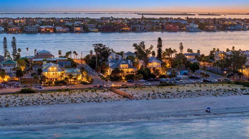 An aerial view shows beach houses along a coastline at dusk with a water view — 106 2ND AVENUE, ST PETE BEACH, FL