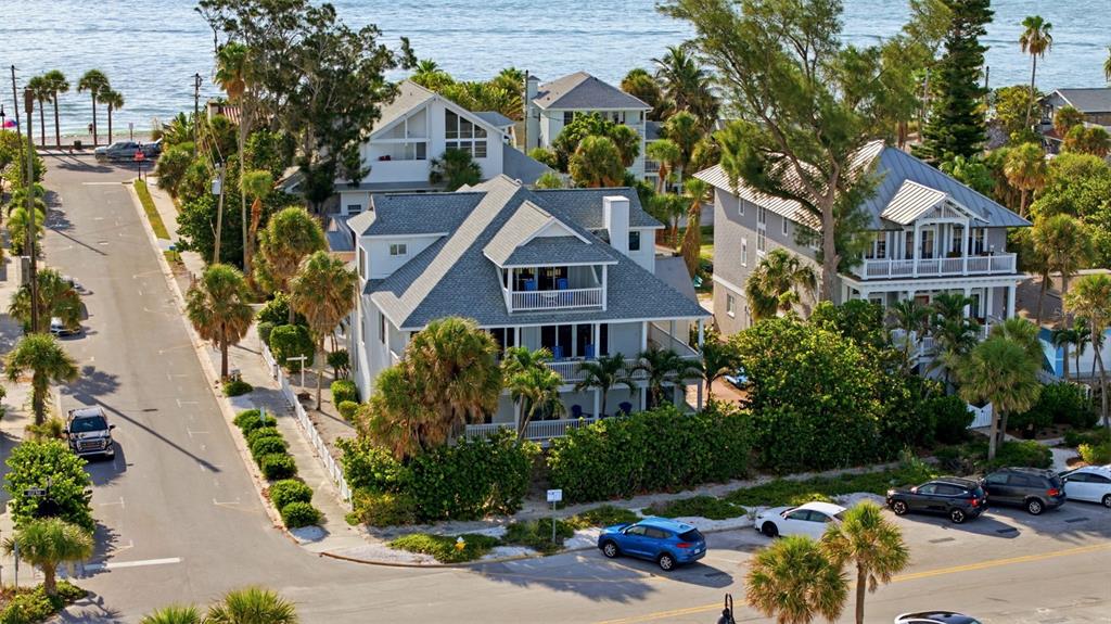 An aerial view shows multi-story coastal homes surrounded by palm trees near a beach — 106 2ND AVENUE, ST PETE BEACH, FL
