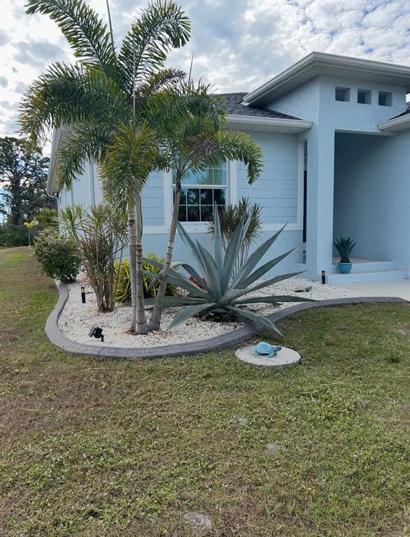 A light blue house exterior features a palm tree, large agave, and decorative turtle statues — 109 FLOWER ROAD, ROTONDA WEST, FL