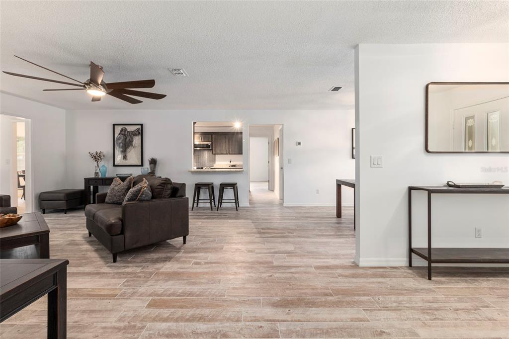 A living room with wood-look tile flooring, a ceiling fan, and an open kitchen pass-through — 1900 NW 73RD TERRACE, OCALA, FL