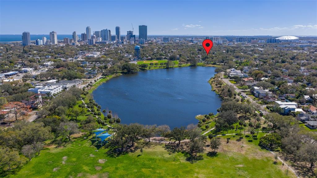 An aerial view shows a lake surrounded by trees, a park, and a city skyline — 711 12TH AVENUE N, ST PETERSBURG, FL