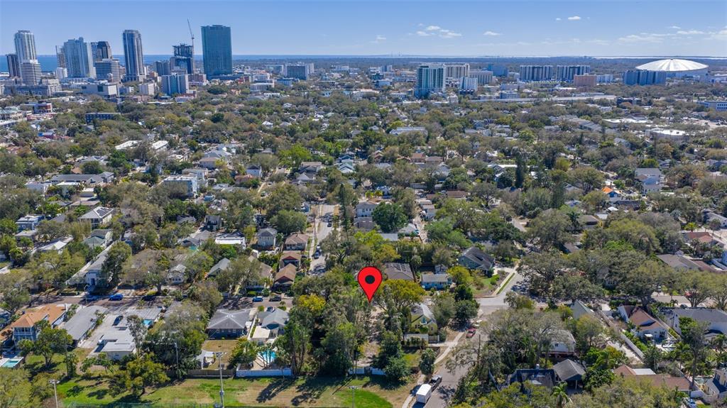 An aerial view shows a vacant residential lot marked with a red pin among trees — 711 12TH AVENUE N, ST PETERSBURG, FL