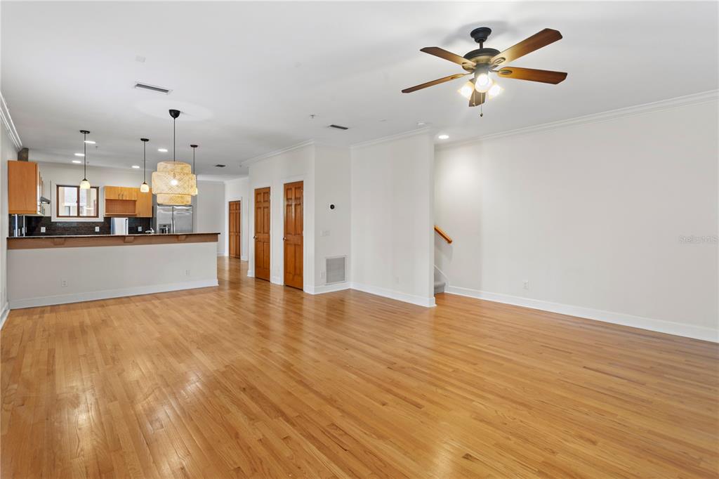 An open-concept living area features hardwood floors, a kitchen with a breakfast bar, and stairs — 512 S GLEN AVENUE, TAMPA, FL