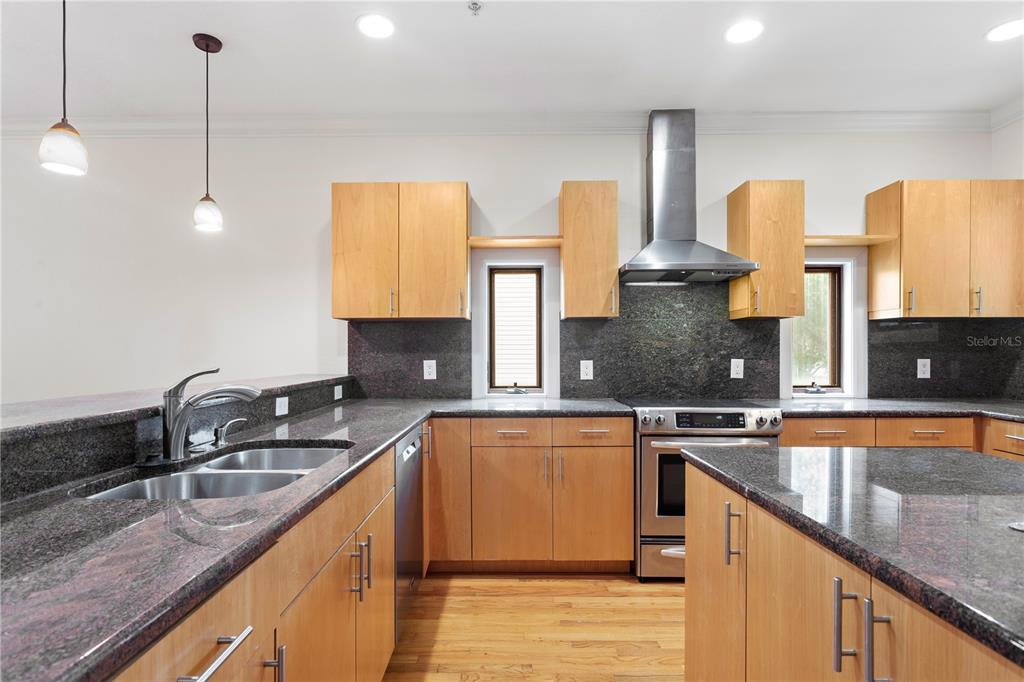 A kitchen features light wood cabinets, dark granite countertops, stainless steel appliances, and hardwood floors — 512 S GLEN AVENUE, TAMPA, FL