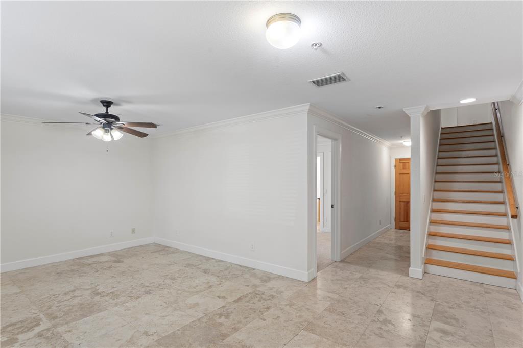 An interior view shows a room with tile flooring, a ceiling fan, and a staircase — 512 S GLEN AVENUE, TAMPA, FL