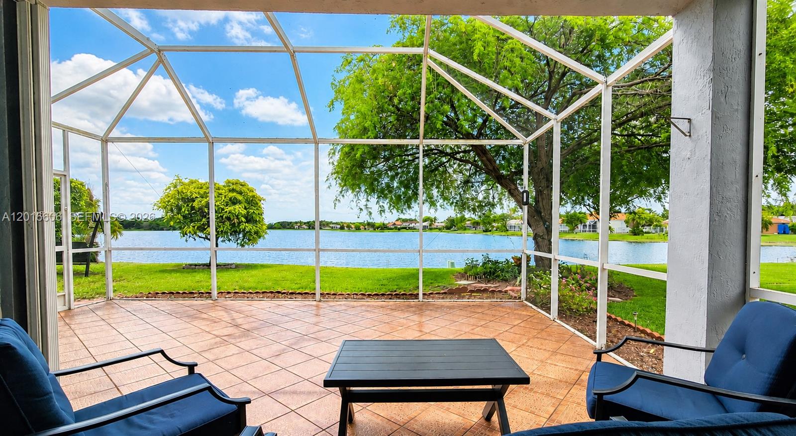 A screened-in patio features tiled flooring, outdoor furniture, and a view of a lake — 963 Falling Water Rd, Weston FL 33326, WESTON, FL