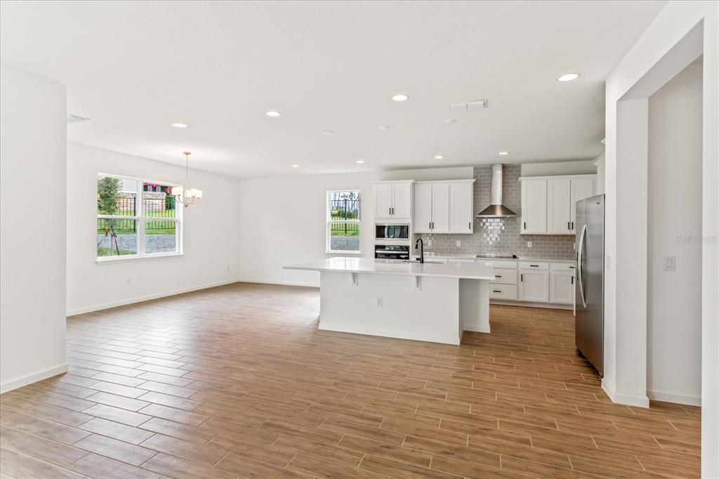 A modern kitchen with white cabinets, a large island, and wood-look tile flooring — 5415 NICKERBEAN STREET, APOPKA, FL