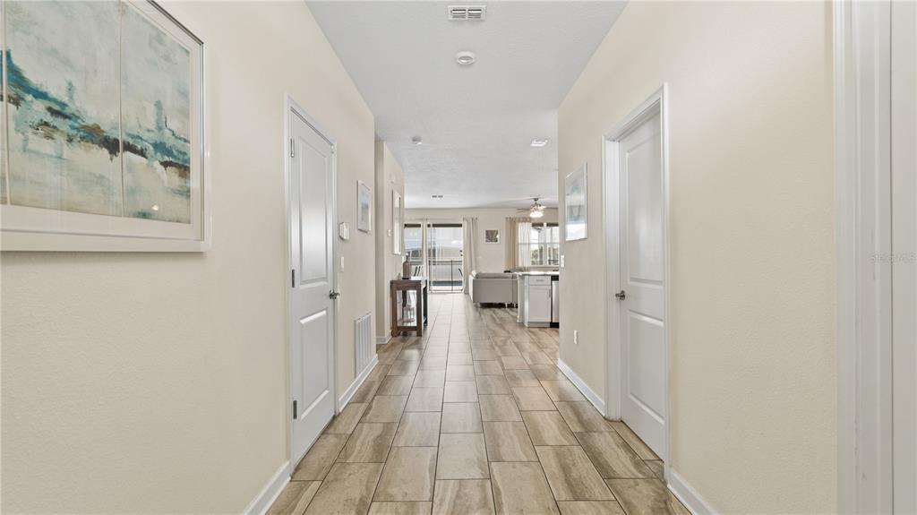 A hallway with tile flooring leads to an open-concept living area with a kitchen — 9098 HAZARD STREET, DAVENPORT, FL